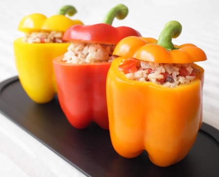 A colorful trio of bell peppers stuffed with rice, mushrooms, and tomatoes の写真素材