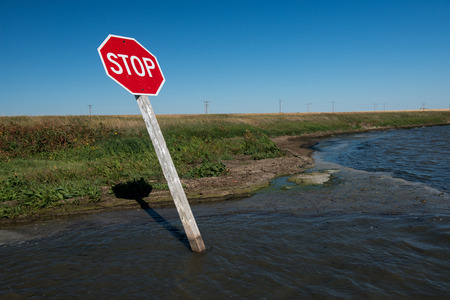 Stop sign at the corner of a flooded road.の写真素材