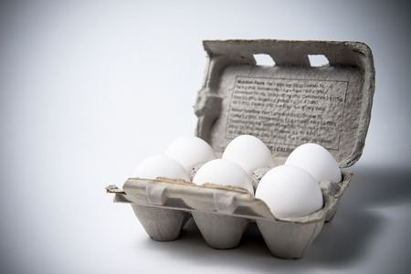 Six white eggs in an older cardboard carton