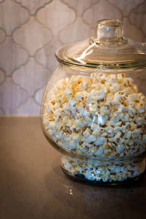 A glass jar on a counter containing popcornの写真素材
