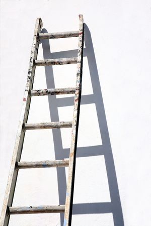 A builders ladder propped against a white wall.の写真素材