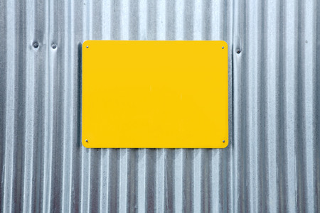 A yellow blank sign on a corrugated iron fence.の写真素材