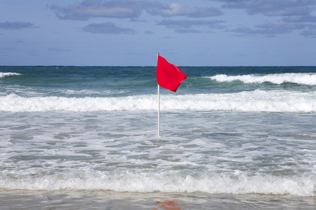 Red dangerous swimming warning lifeguard flag in a rough sea.