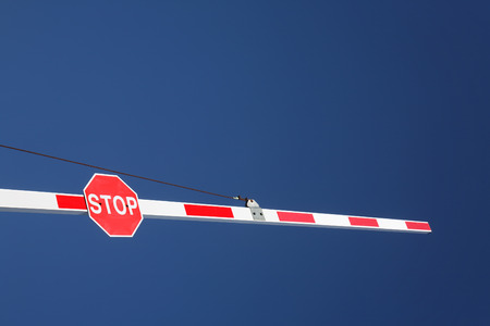A red stop sign on a barrier and a big blue sky.の写真素材