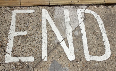 End sign written in white paint on a street pavement.の写真素材