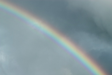 Colorful rainbow in a dark cloudy sky.の写真素材