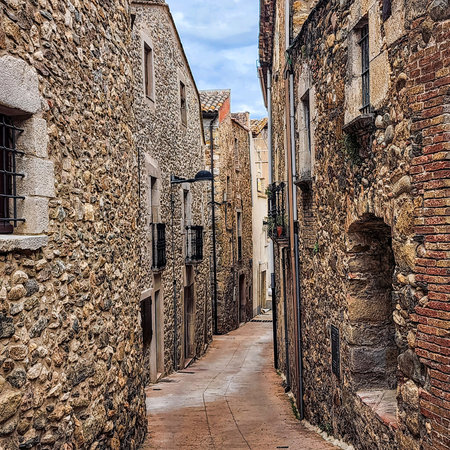 Narrow streets of the old town. Old stonework on facades with gates and balconies. Cityscape. Celra. Catalonia. Spain.の写真素材
