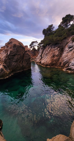 Seascape with calm water surface and rocks. Turquoise transparent water. Evening on the...