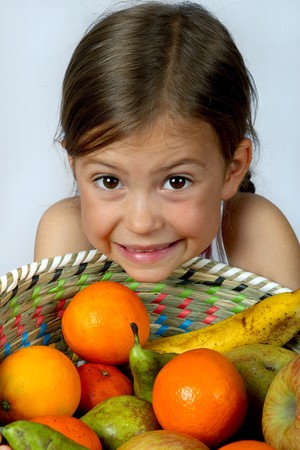 Little girl showing delight over a basket of fruitの写真素材