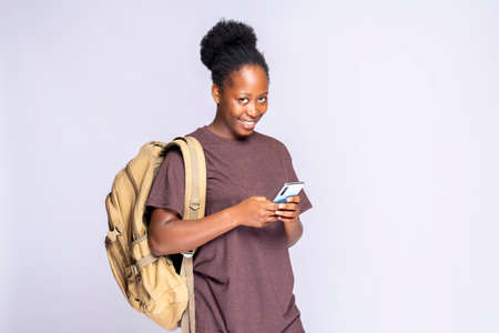 Excellent application. Portrait of a happy black african woman holding a smartphone against a white...