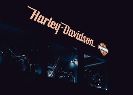 Harley Davidson logo on a dealership at night, with chopper motorbikes on display.のeditorial素材