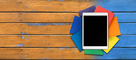 tablet, books in rainbow colors on the table from the old boards, front viewの写真素材