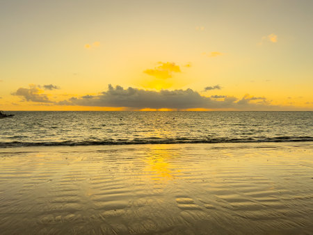 It's just before sunrise at the beach with some clouds in the orange skyの写真素材