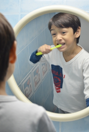 Kid brushing his teeth at mirrowの写真素材