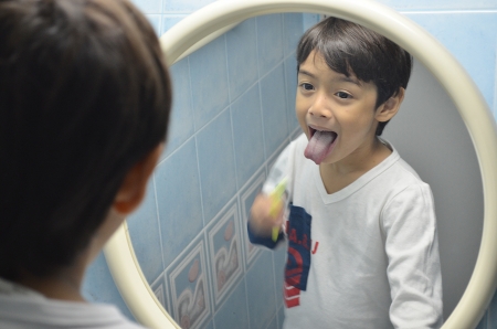 Kid brushing his teeth at mirrowの写真素材