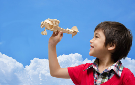 little boy playing airplane wood toy with blue skyの写真素材