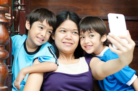 Mother and sons taking selfie with mobile in houseの写真素材