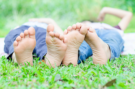 Little boy lay on grass show feet in the parkの写真素材