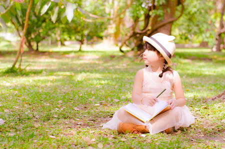 Little girl holding book in the parkの写真素材
