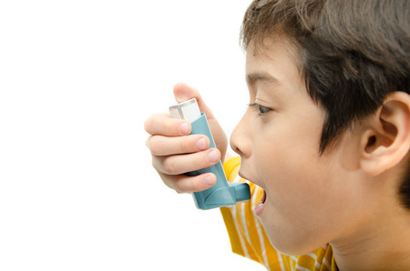 Little boy using Asthma inhaler for breathing on white backgroundの写真素材