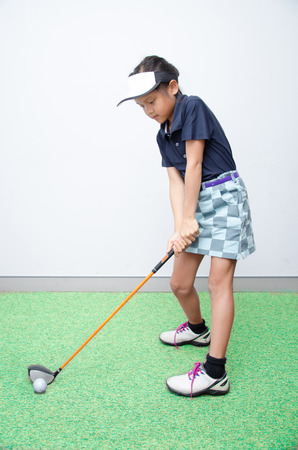 Little asian girl takine golf club trainingの写真素材