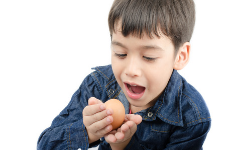 Little boy holding egg in hand mouth wide healthy on white backgroundの写真素材