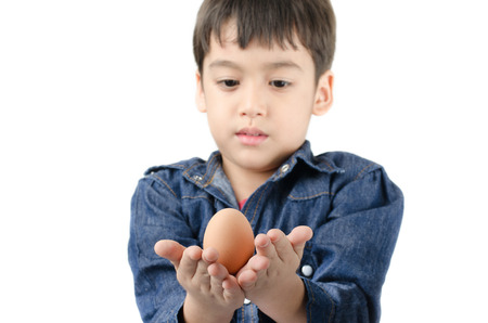 Little boy holding egg in hand healthy focus on egg on white backgroundの写真素材