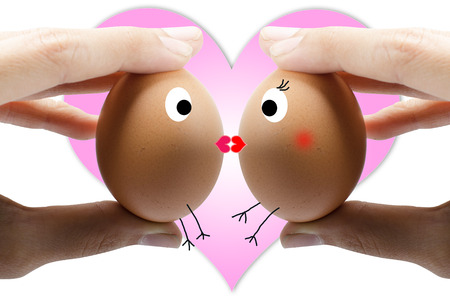 hand holding two eggs kissing with pink heart backgroundの写真素材