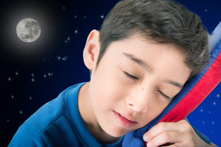 Little boy sleeping in bed with night backgroundの写真素材