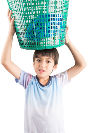 Little boy taking basket of dirty cloths to washの写真素材