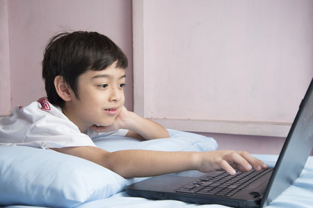 Little boy using notebook laptop in the bedroomの写真素材