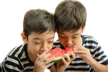 Little sibling boy eating watermelon togetherの写真素材