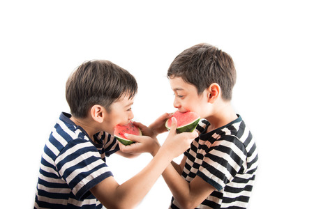 Little sibling boy eating watermelon togetherの写真素材