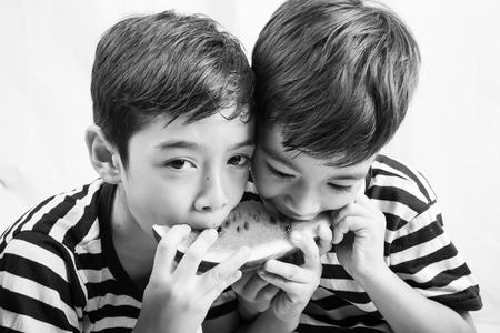 Little sibling boy eating watermelon togetherの写真素材