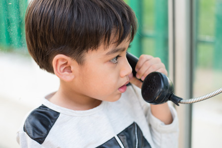 Little boy using public phone outdoor emergencyの写真素材