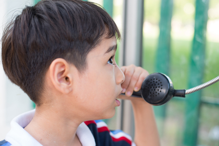 Little boy using public phone outdoor emergencyの写真素材
