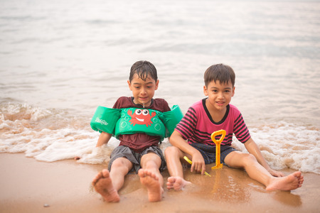 Little boy sitting together on the beachの写真素材