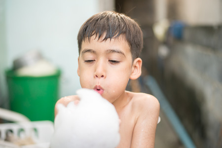 Little boy showering with foam bath outdoorの写真素材