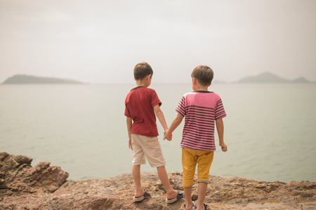 Little boy standing together on the beachの写真素材