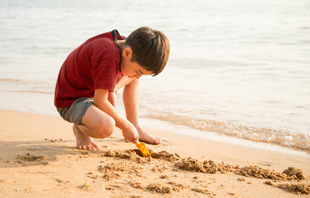 Little boy playing sand on the beach summer timeの写真素材