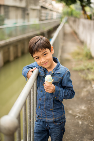 Little boy walking and eating icecream on the streetの写真素材