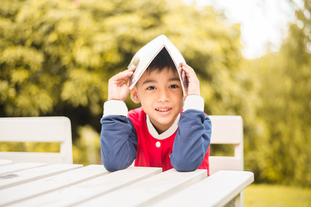 Little boy reading book in the parkの写真素材