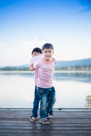 Little sibling boy standing together nearby lagoonの写真素材