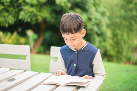 Little boy reading book in the parkの写真素材