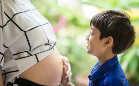Little boy listen mother tummy pregnant new babyの写真素材