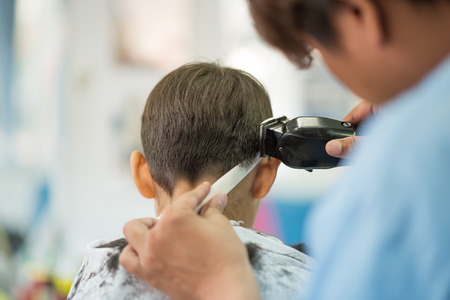 Little boy sitting for hair cut at barber shopの写真素材