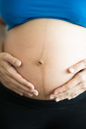 close-up, belly and hands of the pregnant woman standing hand touchingの写真素材