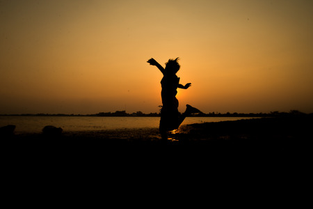 Little boy jumping before the sunset silhouetteの写真素材