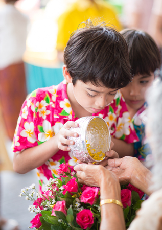 Little boy pouring water on older hand Thailand water festival ,Songkranの写真素材