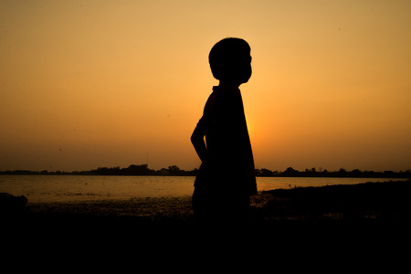 Little boy jumping before the sunset silhouetteの写真素材